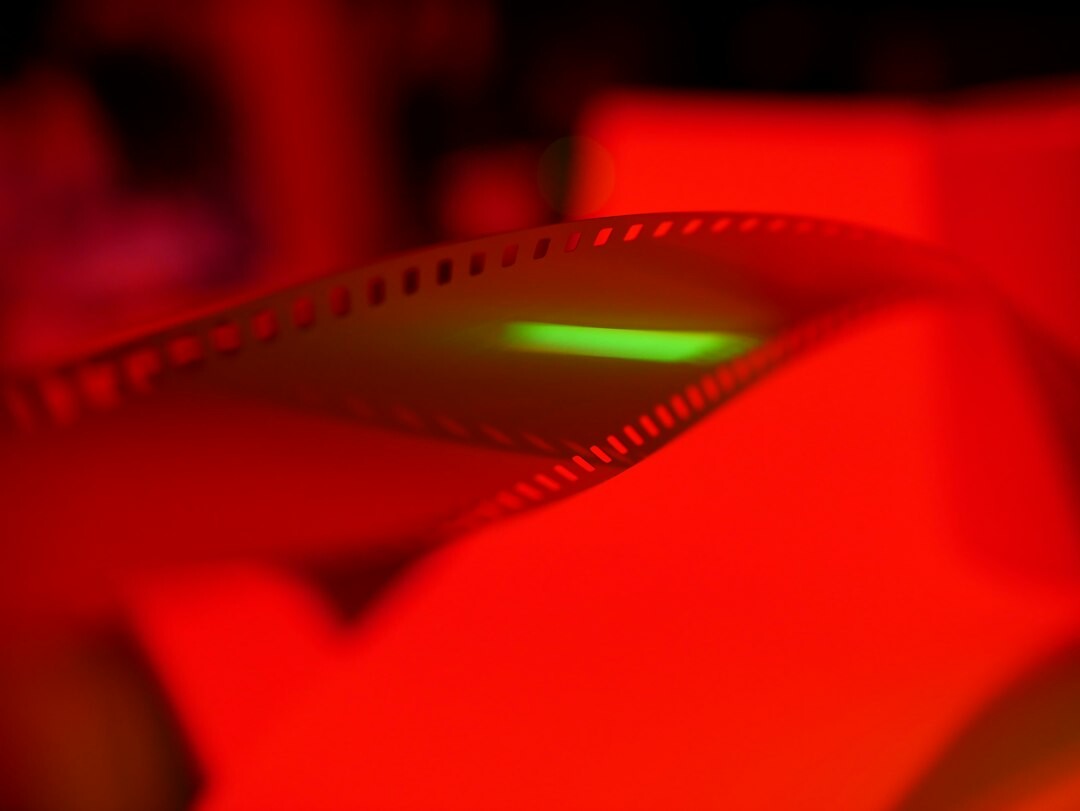 Photographer developing film in a red-lit darkroom